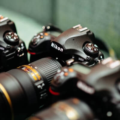 three cameras sitting diagonally, with only the center, a Nikon, in focus