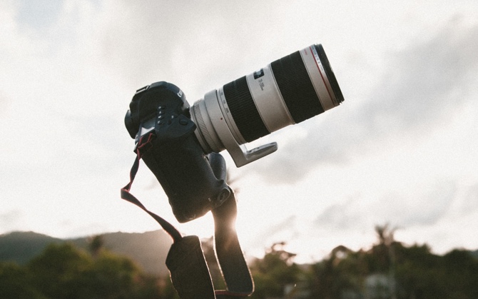 camera with long lens appears to be floating as sun sets behind a mountain